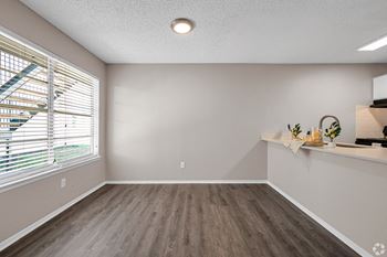 An empty living room with a large window and wood flooring